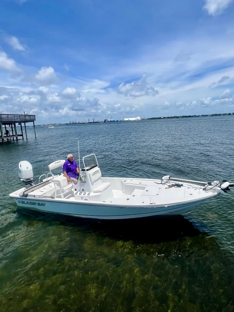 The Image of 2021 Blazer Bay 2200 boat on calm water under a clear blue sky. - 0