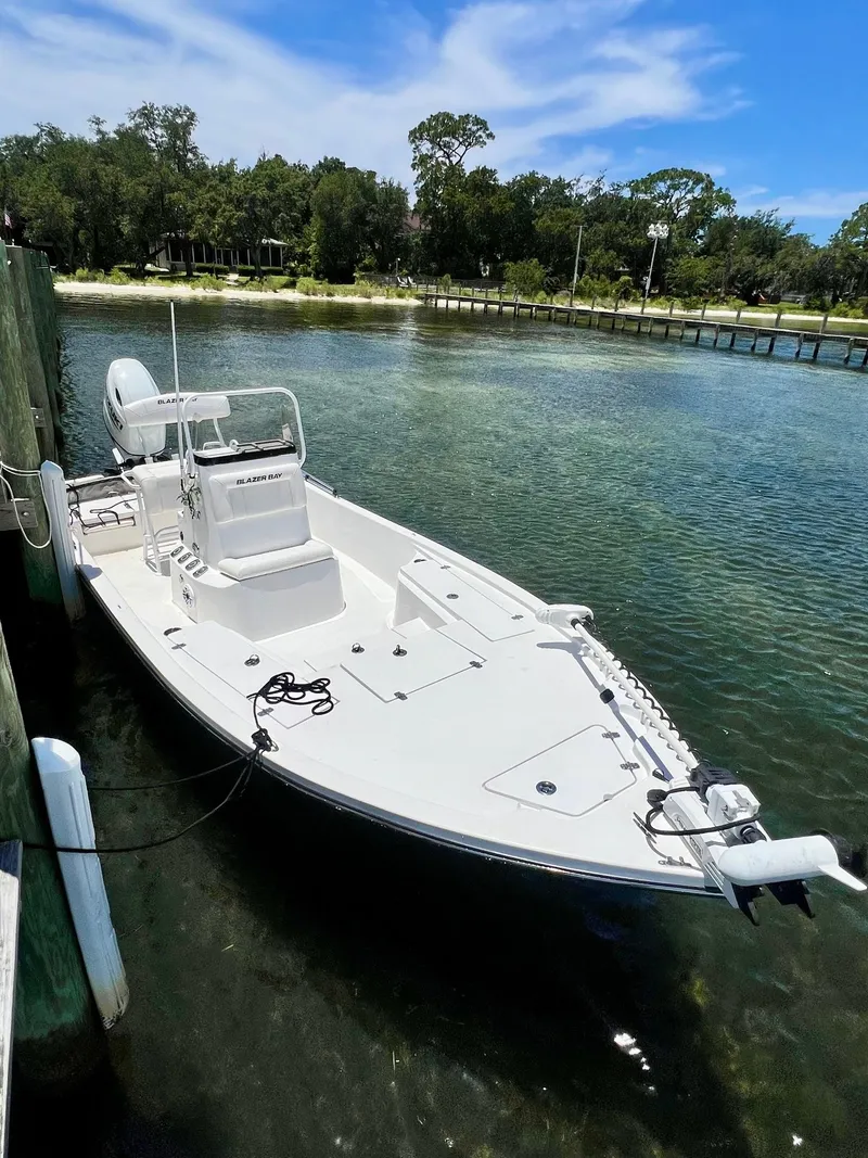 Slide: The Image of 2021 Blazer Bay 2200 boat docked in clear water, surrounded by trees. - 11