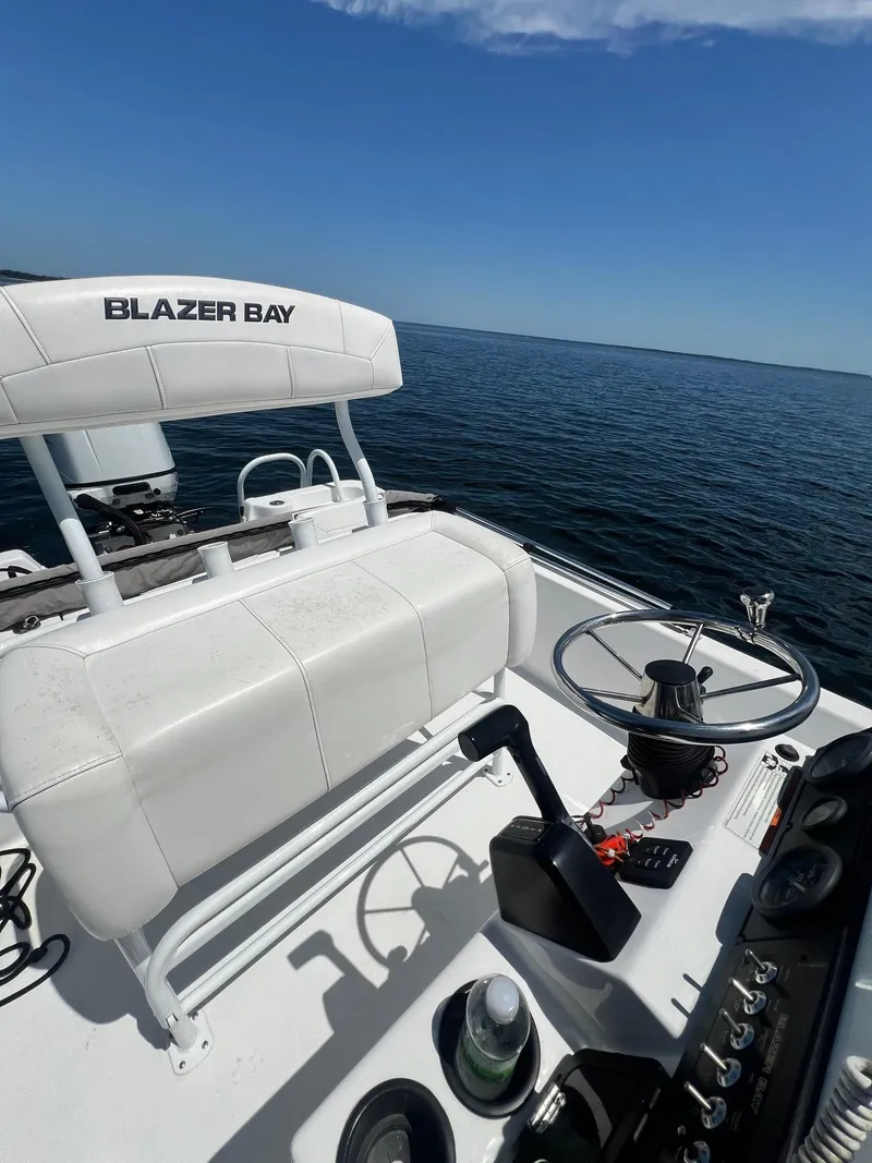 Slide: The Image of 2021 Blazer Bay 2200 boat interior with steering wheel, white seating, and ocean view. - 18