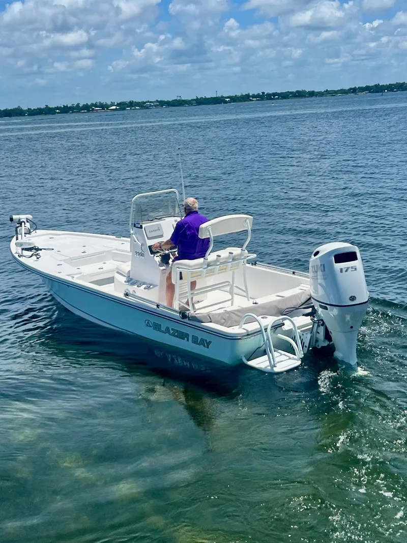 Slide: The Image of 2021 Blazer Bay 2200 boat on water, person steering, clear sky, calm sea. - 3