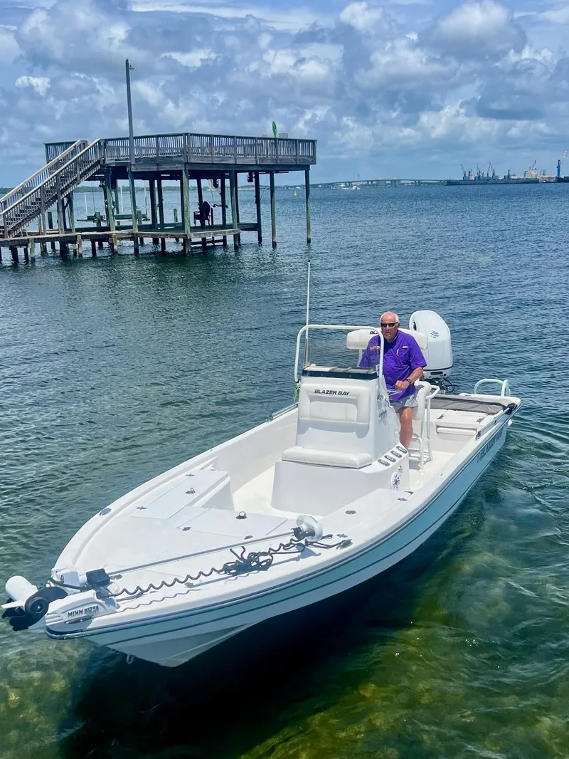 Slide: The Image of Man on 2021 Blazer Bay 2200 boat near dock, under cloudy sky. - 7