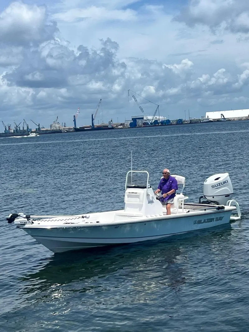 Slide: The Image of A 2021 Blazer Bay 2200 boat on water with a person onboard, industrial background. - 9