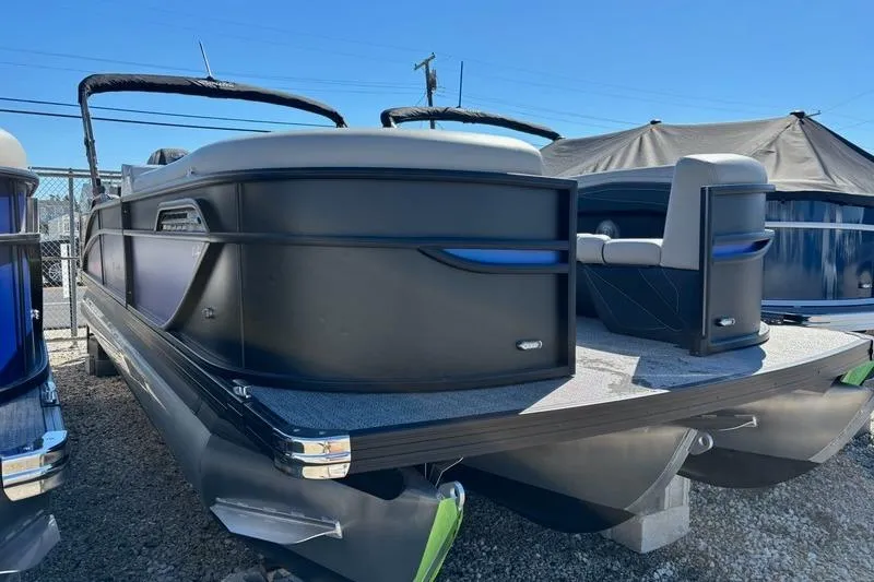 Slide: The Image of 2026 Barletta C24M pontoon boat with sleek black design, docked outdoors. - 2