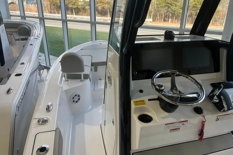 Slide: The Image of 2025 Sportsman Masters 227 Bay Boat interior with steering console and seating, displayed indoors. - 4
