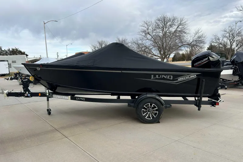 Slide: The Image of 2026 Lund 1800 Explorer Sport boat with cover on trailer, parked outdoors. - 0