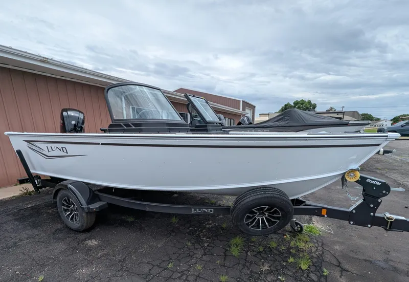 Slide: The Image of 2026 Lund 1800 Explorer Sport boat with cover on trailer, parked outdoors. - 1