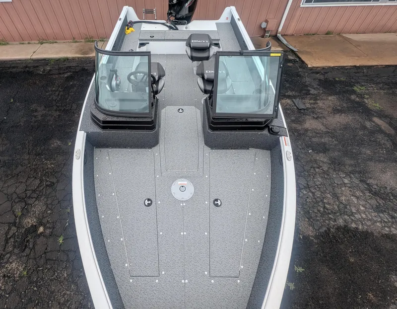 Slide: The Image of 2026 Lund 1800 Explorer Sport boat with outboard motor, covered and parked outside dealership. - 2