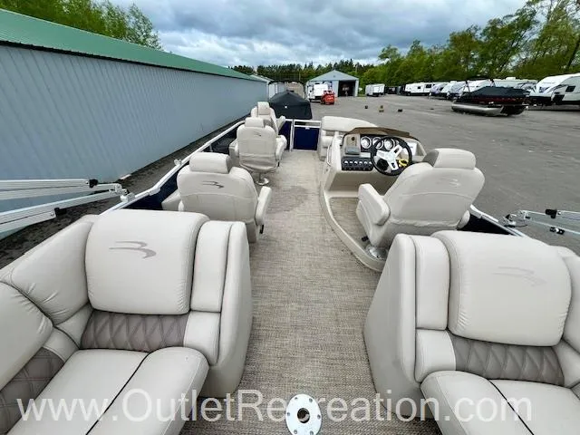Slide: The Image of 2017 Bennington R23 pontoon boat with beige seating, parked outdoors near storage units. - 17