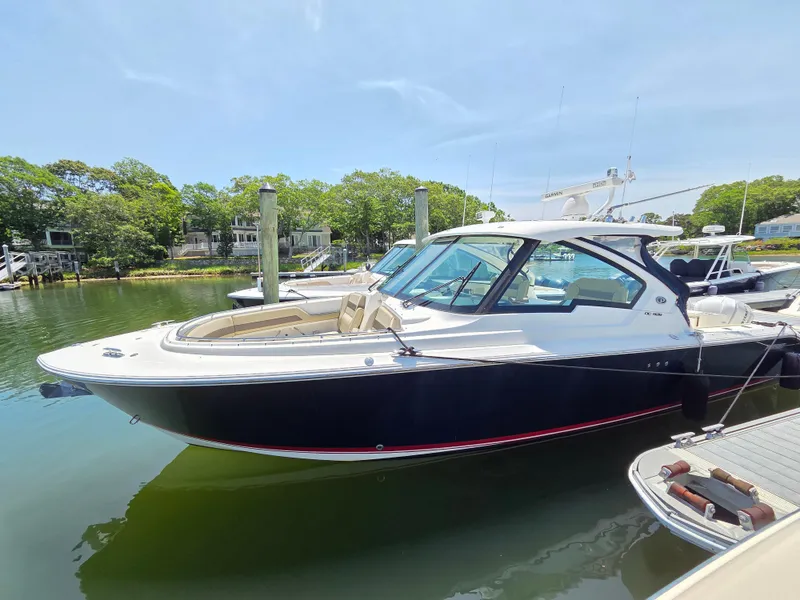 The Image of 2020 Pursuit DC 326 Dual Console boat docked in a serene marina setting. - 0