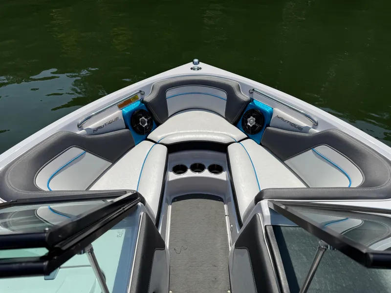Slide: The Image of 2014 Nautique Sport 200 boat interior with cushioned seating and cup holders on a calm lake. - 16