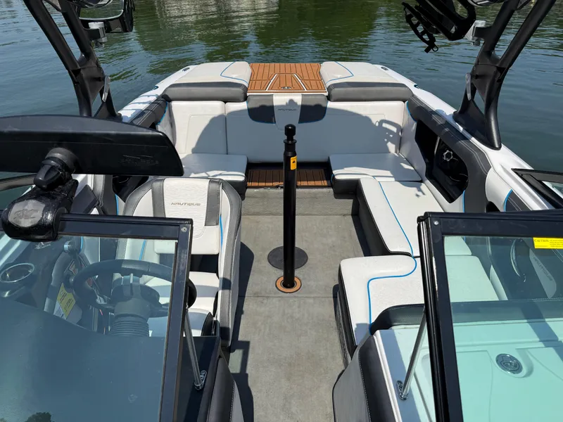 Slide: The Image of 2014 Nautique Sport 200 boat interior with seating and steering wheel, on calm water. - 19