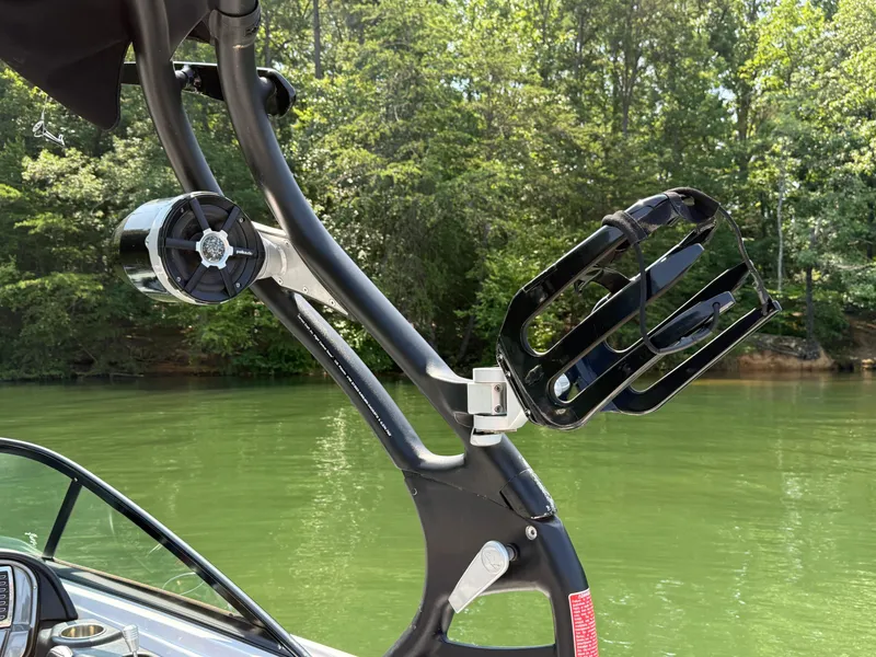 Slide: The Image of 2014 Nautique Sport 200 boat with wakeboard rack and speaker on a calm lake. - 21