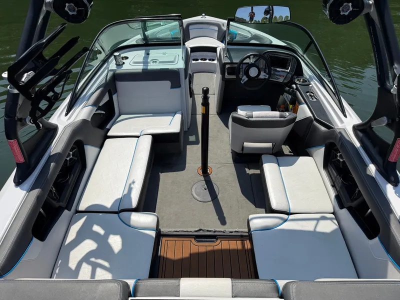 Slide: The Image of 2014 Nautique Sport 200 boat interior with seating and steering wheel, docked on water. - 9