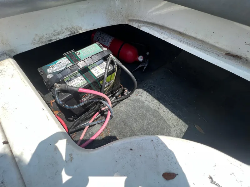 Slide: The Image of 2004 MasterCraft MariStar 210 VRS battery compartment with marine battery and fire extinguisher. - 29