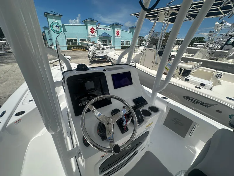 Slide: The Image of 2025 Sea Pro 230 Bay boat dashboard with steering wheel and controls at a yacht dealership. - 4