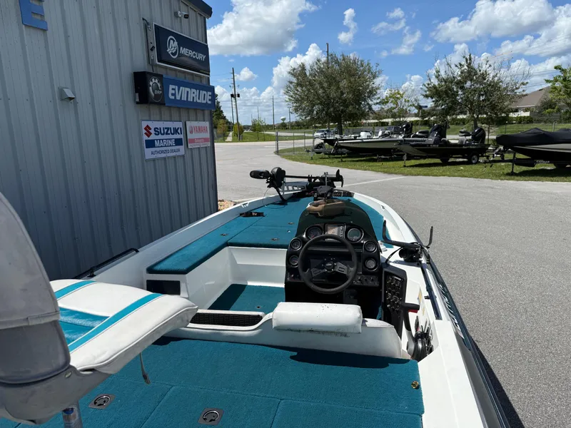 Slide: The Image of 1995 Stratos 201XL boat with blue interior, parked near marine dealership signs. - 10