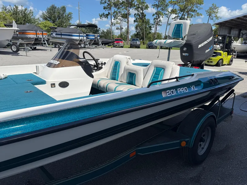 Slide: The Image of 1995 Stratos 201XL boat with teal accents and Mercury engine, parked outdoors. - 4