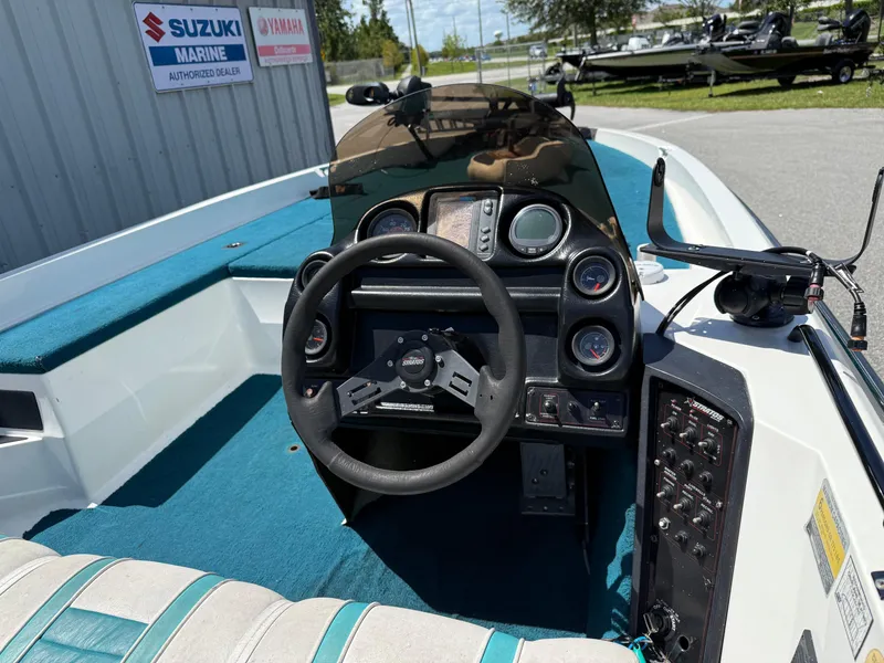 Slide: The Image of 1995 Stratos 201XL boat dashboard with steering wheel and control panel, near Suzuki and Yamaha dealer signs. - 9