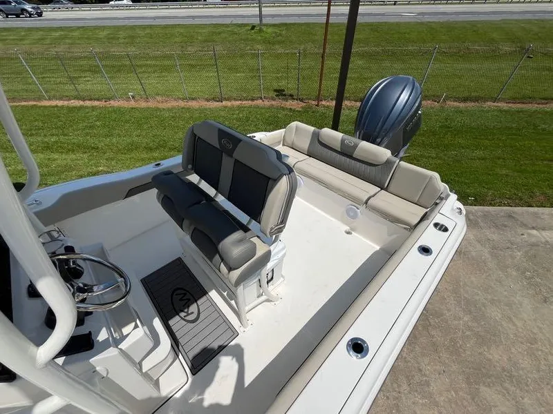 Slide: The Image of 2025 Key West 239 FS boat interior with seating and steering wheel, parked on concrete. - 7