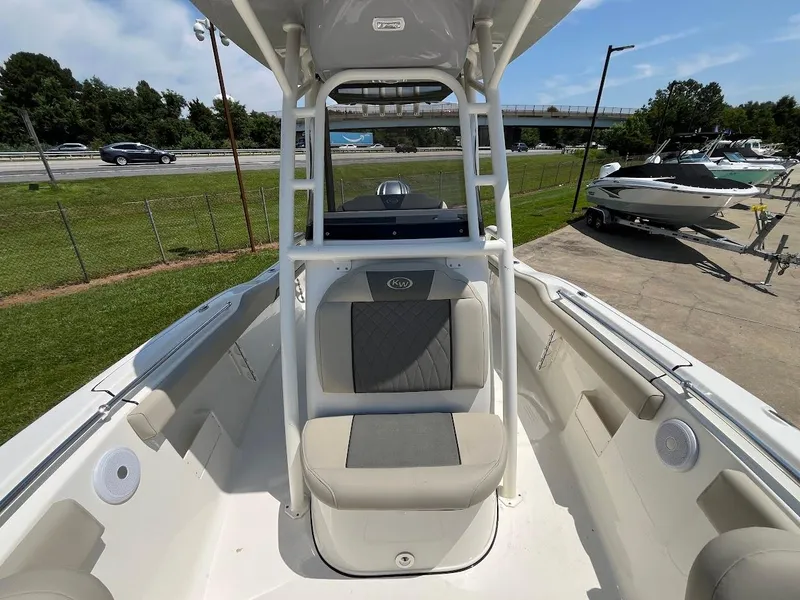 Slide: The Image of 2025 Key West 239 FS boat interior with seating and console, parked near highway. - 8