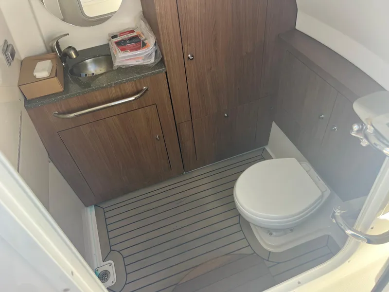 Slide: The Image of 2017 Boston Whaler 350 Outrage bathroom with wood cabinets, sink, and toilet. - 21