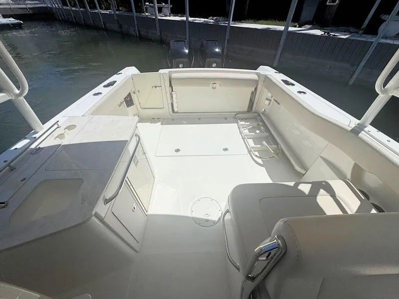 Slide: The Image of 2016 Boston Whaler 270 Vantage boat interior with seating and storage, docked by the water. - 12