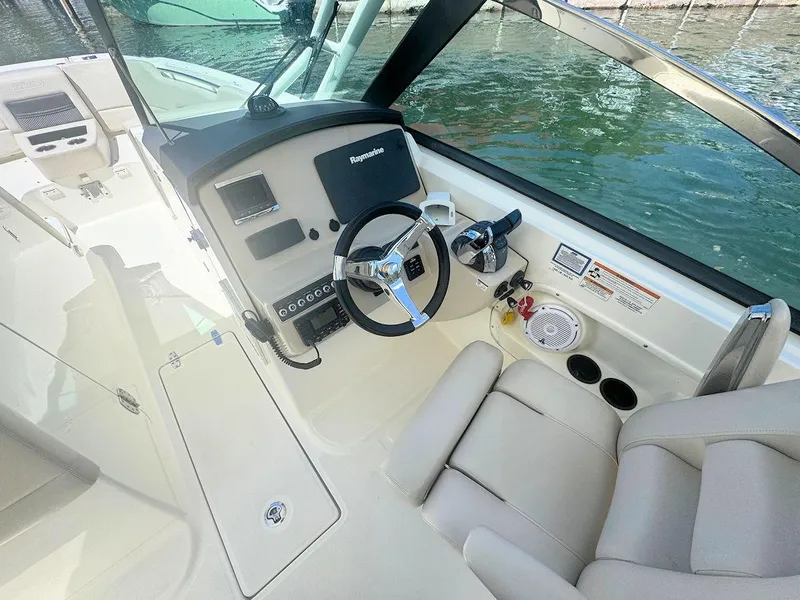 Slide: The Image of 2016 Boston Whaler 270 Vantage helm with steering wheel and controls, docked by water. - 16