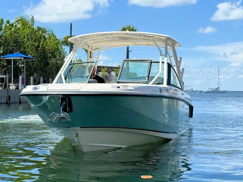 Slide: The Image of 2016 Boston Whaler 270 Vantage boat on water, clear sky, and lush greenery. - 5