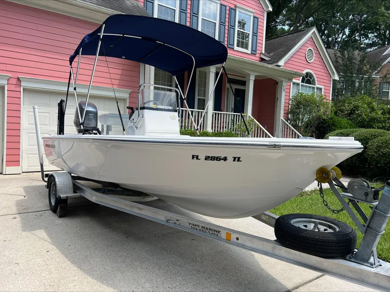 Slide: The Image of 2016 Sportsman Island Bay 18 boat on trailer, parked in front of a pink house. - 1