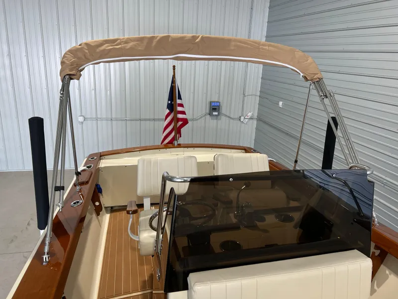 Slide: The Image of 1974 Chris-Craft Dory boat interior with American flag and beige canopy in a garage. - 13