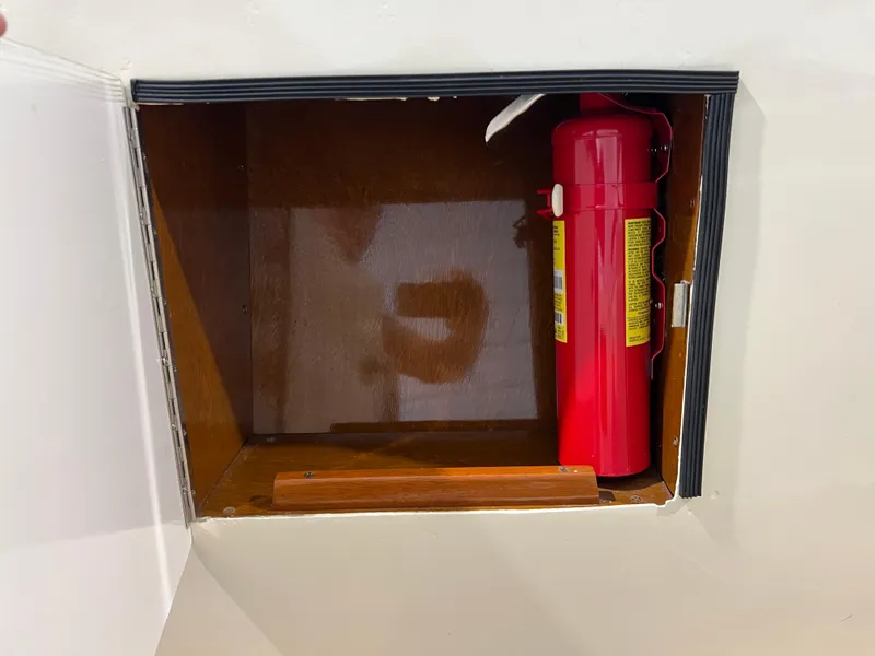 Slide: The Image of Red fire extinguisher in a wooden compartment of a 1974 Chris-Craft Dory boat. - 25