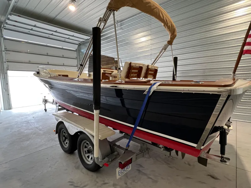 Slide: The Image of 1974 Chris-Craft Dory boat on trailer in a garage, featuring classic design and American flag. - 5