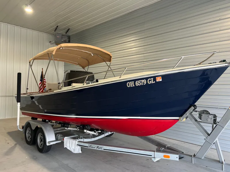 Slide: The Image of 1974 Chris-Craft Dory boat on trailer in garage, blue and red hull, tan canopy. - 7