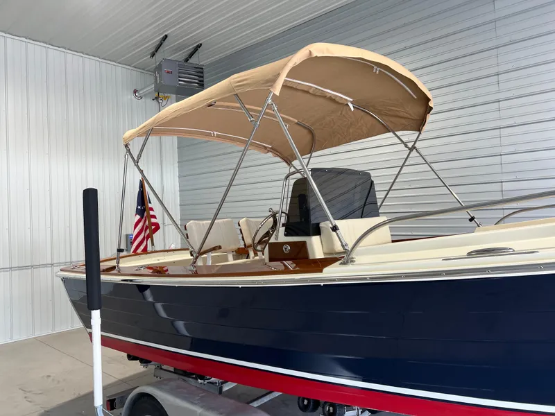 Slide: The Image of 1974 Chris-Craft Dory boat with canopy in a garage, featuring a classic design. - 8