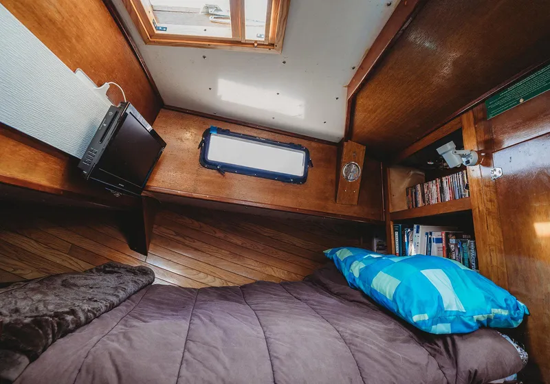 Slide: The Image of Cozy cabin interior of 1991 Trawler 37 with bed, books, and small TV. - 27