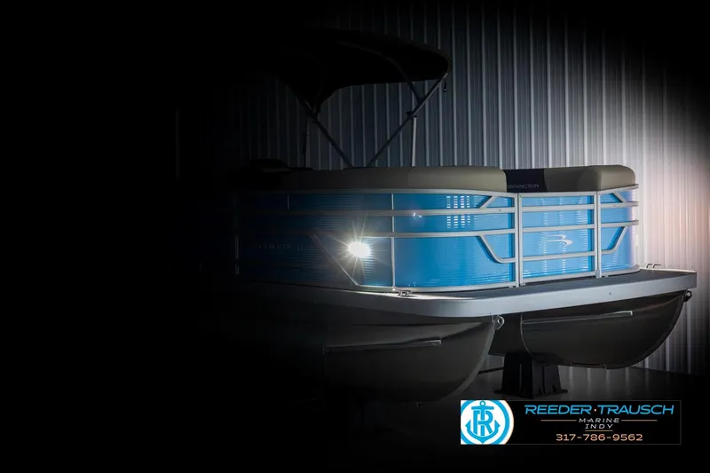 Slide: The Image of 2025 Bennington 21 SL pontoon boat in dimly lit showroom, side view. - 3