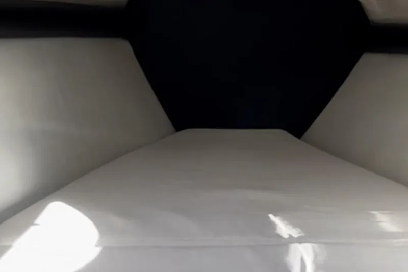 Slide: The Image of Interior cabin view of a 1997 Baja 38 boat, featuring a white cushioned bed. - 23