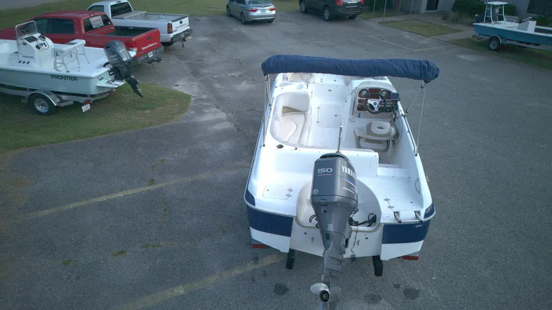 Slide: The Image of 2010 NauticStar 210 SC boat with Yamaha 150 engine, parked in a lot. - 2