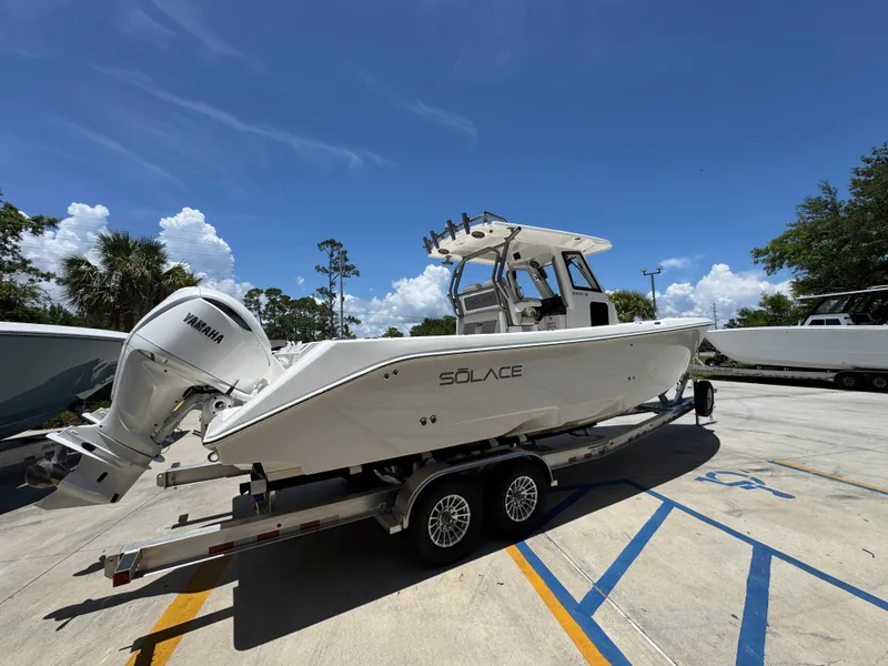 Slide: The Image of 2026 Solace 30 CS boat on trailer with Yamaha engine, parked outdoors under blue sky. - 11