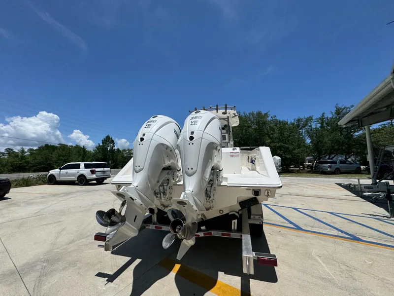 Slide: The Image of 2026 Solace 30 CS boat with dual outboard engines on a trailer in a sunny parking lot. - 13