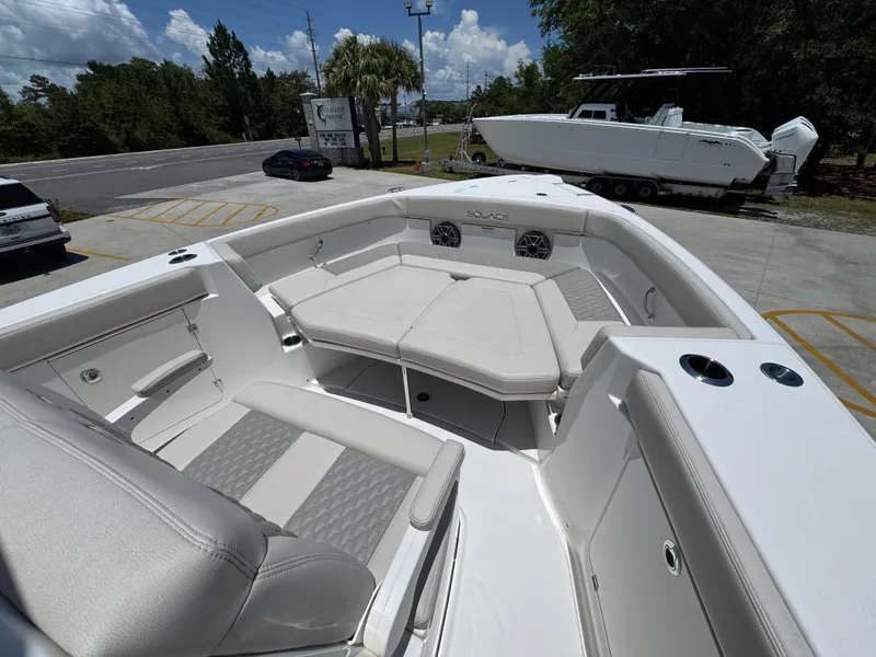 Slide: The Image of 2026 Solace 30 CS boat interior with cushioned seating and cup holders, parked outdoors. - 17
