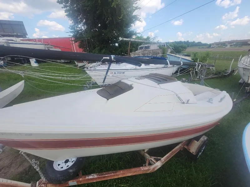Slide: The Image of 1986 O'Day 19 sailboat on trailer, parked on grass under a blue sky. - 10