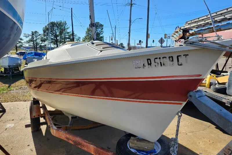 Slide: The Image of 1986 O'Day 19 sailboat on trailer, featuring red stripe, parked outdoors. - 18