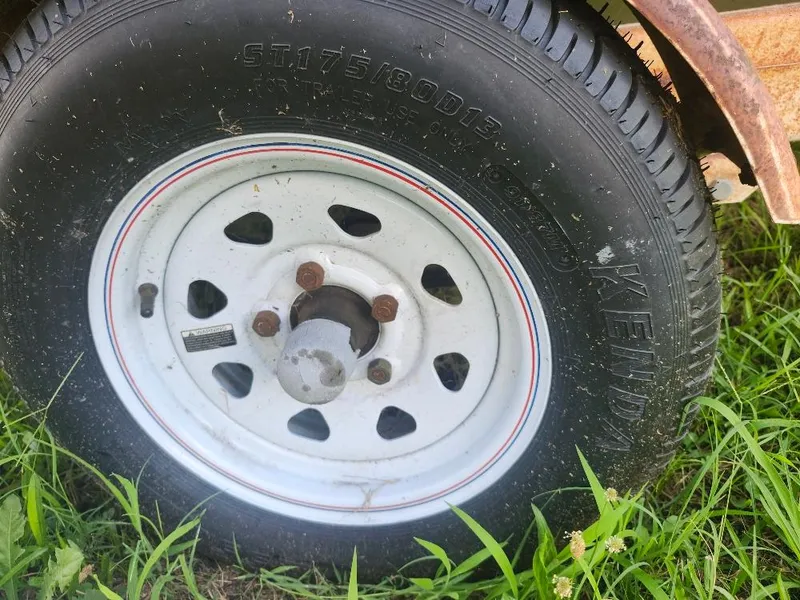 Slide: The Image of Trailer tire with white rim on grass, featuring Kenda brand and size ST175/80D13. - 7