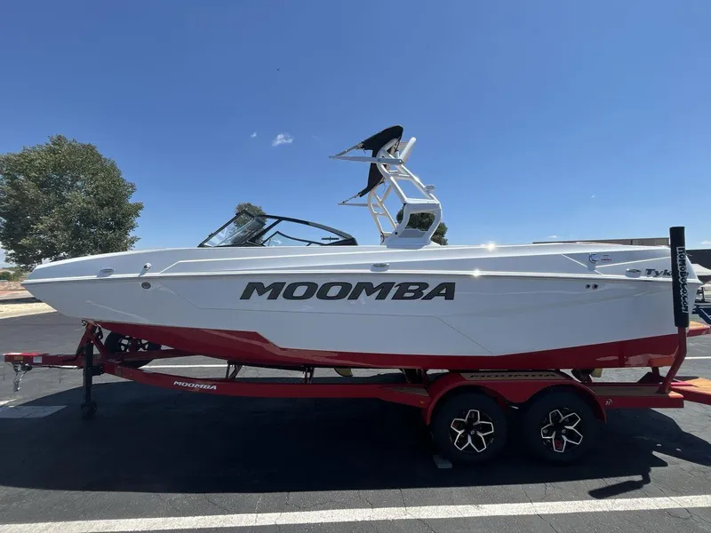 Slide: The Image of 2025 Moomba Tykon boat on red trailer under clear blue sky. - 2
