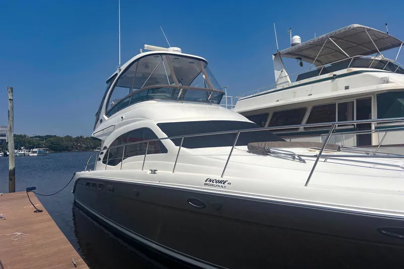 Slide: The Image of 2006 Sea Ray 52 Sedan Bridge yacht docked at marina under clear blue sky. - 2