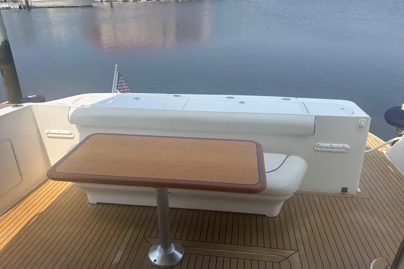Slide: The Image of 2006 Sea Ray 52 Sedan Bridge yacht deck with wooden table and seating by the water. - 30