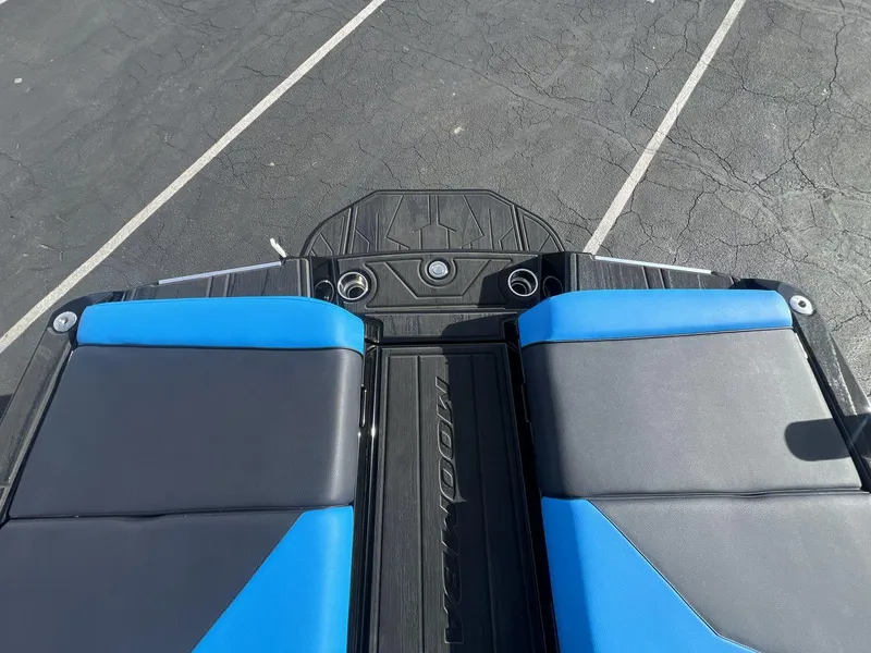 Slide: The Image of 2025 Moomba Mojo boat interior with blue and black seating, docked on asphalt. - 19