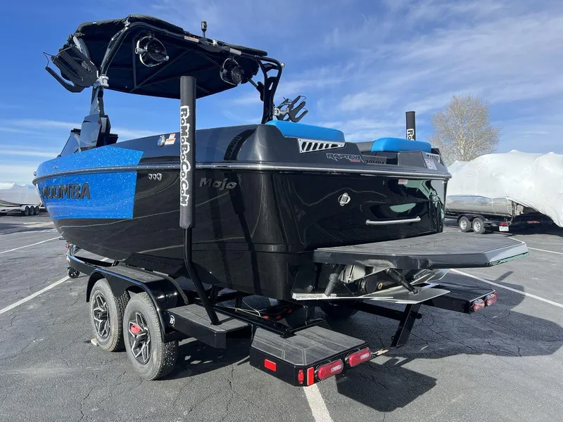 Slide: The Image of 2025 Moomba Mojo boat on trailer, featuring sleek black and blue design, parked outdoors. - 3