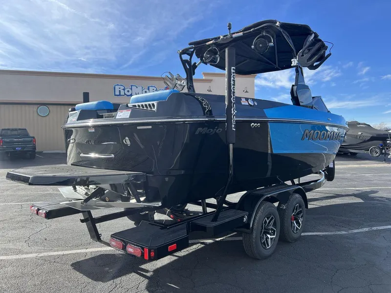 Slide: The Image of 2025 Moomba Mojo boat on trailer, parked outdoors, featuring sleek black and blue design. - 5